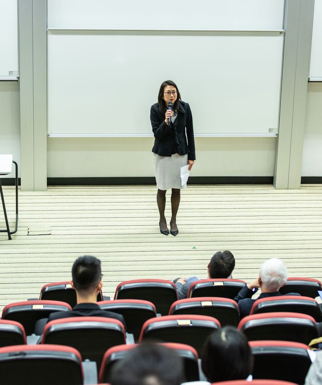 Ponente dirigiéndose con micrófono a un auditorio