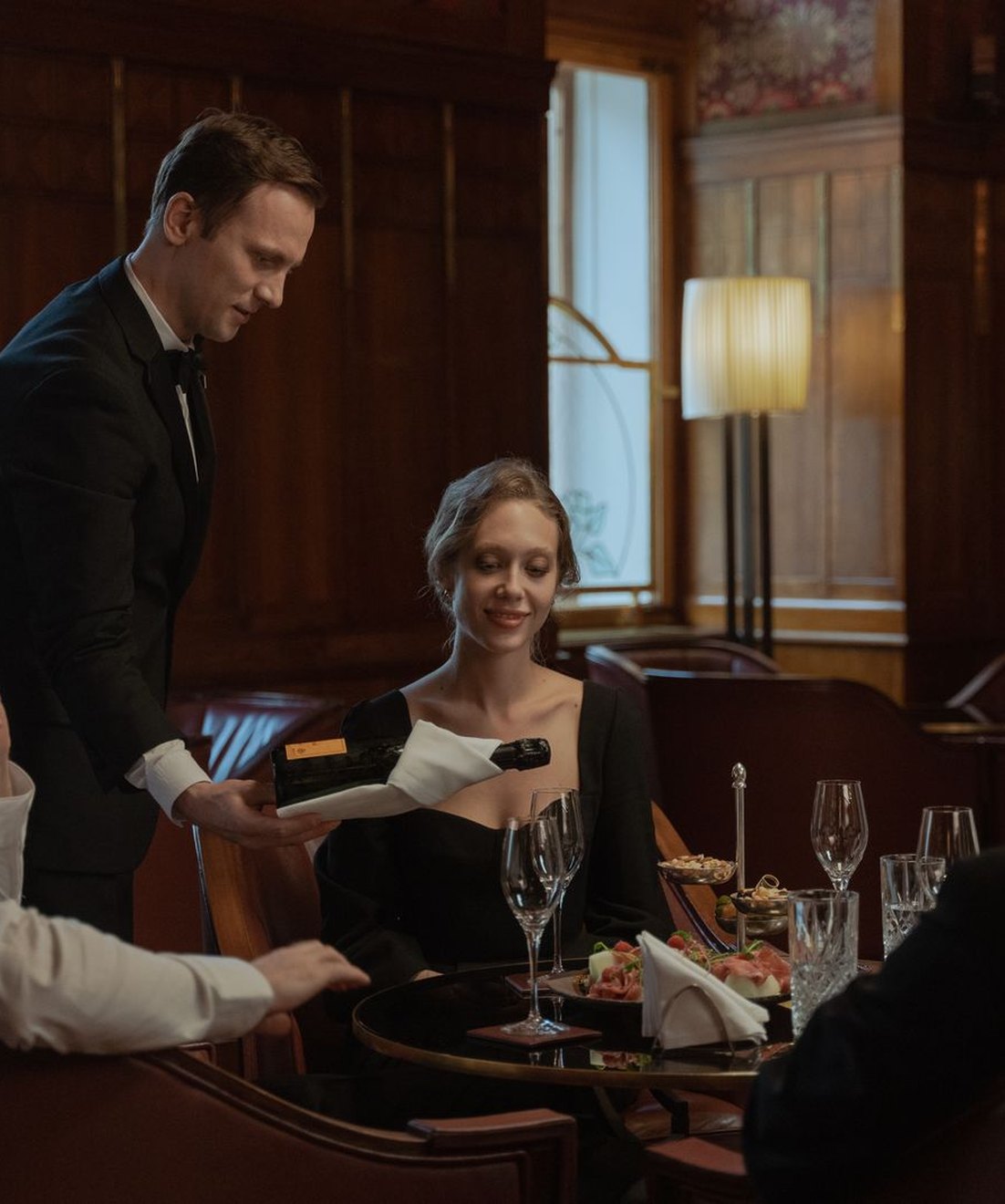 Maître atendiendo a un grupo de clientes en el comedor de un restaurante