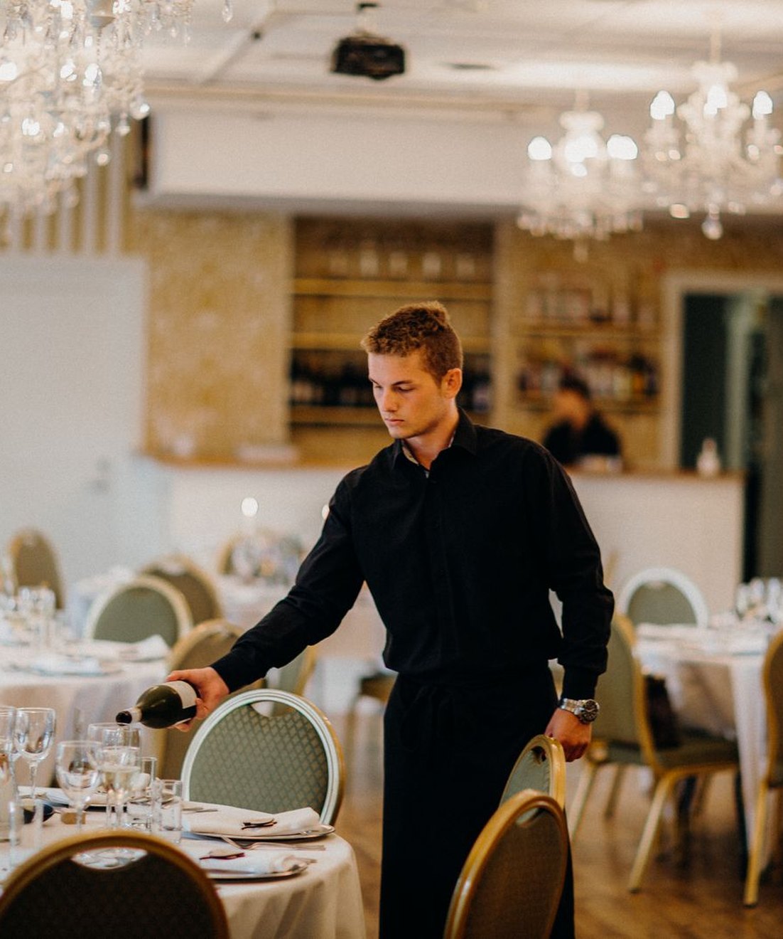 Camarero preparando las mesas de un salón de banquetes
